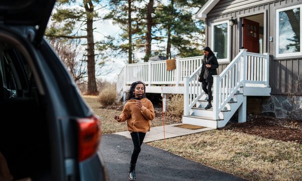 little girl running from house to car with mother in background